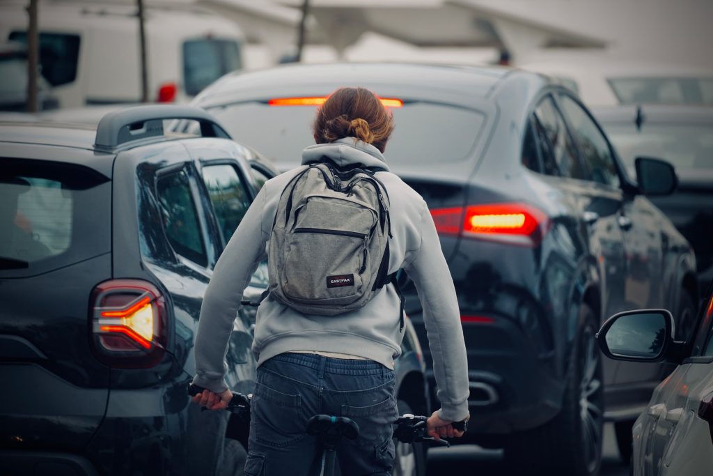 Un cycliste portant un sac à dos roule dans un embouteillage urbain en pleine journée. Photo par Soufiane Chafiq